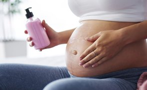 mulher gravida passando creme na barriga