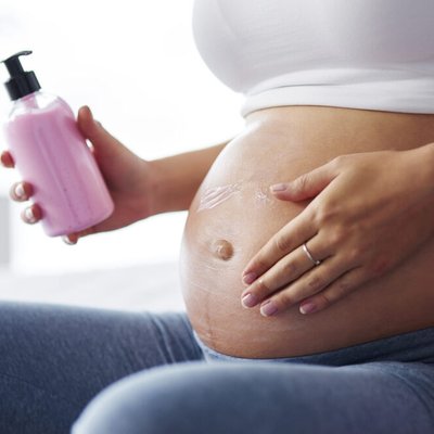 mulher gravida passando creme na barriga