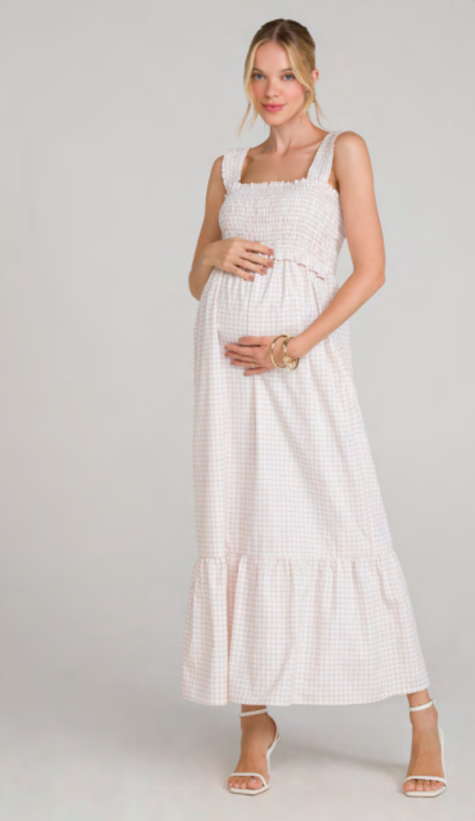 modelo com as duas maos na barriga usando vestido branco com quadriculado rosa