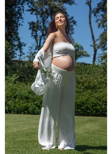 modelo em ambiente aberto com top e camisa branca e calca comfy cos lastex branca