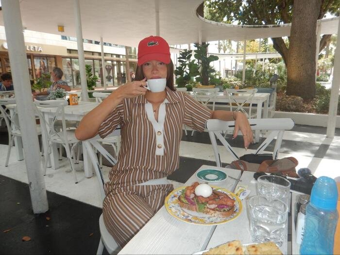 modelo com conjunto de blusa polo e calca em malha listrado marrone 108 marrom bebendo uma xicara de cafe