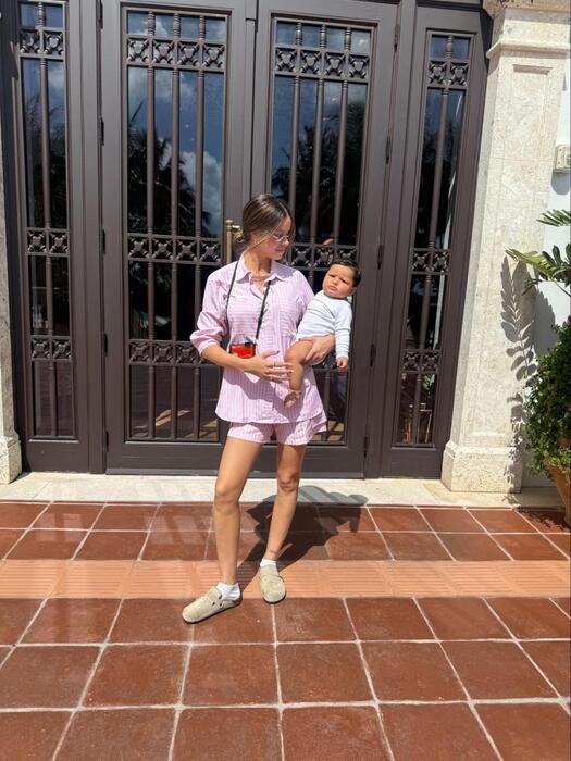 modelo usando conjunta de camisa e shorts listrado colore 306 rosa segurando filho no colo